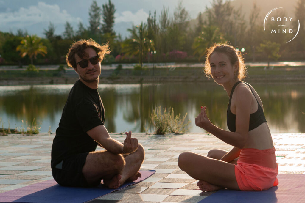 Sunset yoga by the lake at BodyvaMind Retreat in Vietnam, with two german guests in meditative poses surrounded by nature’s calm glow.